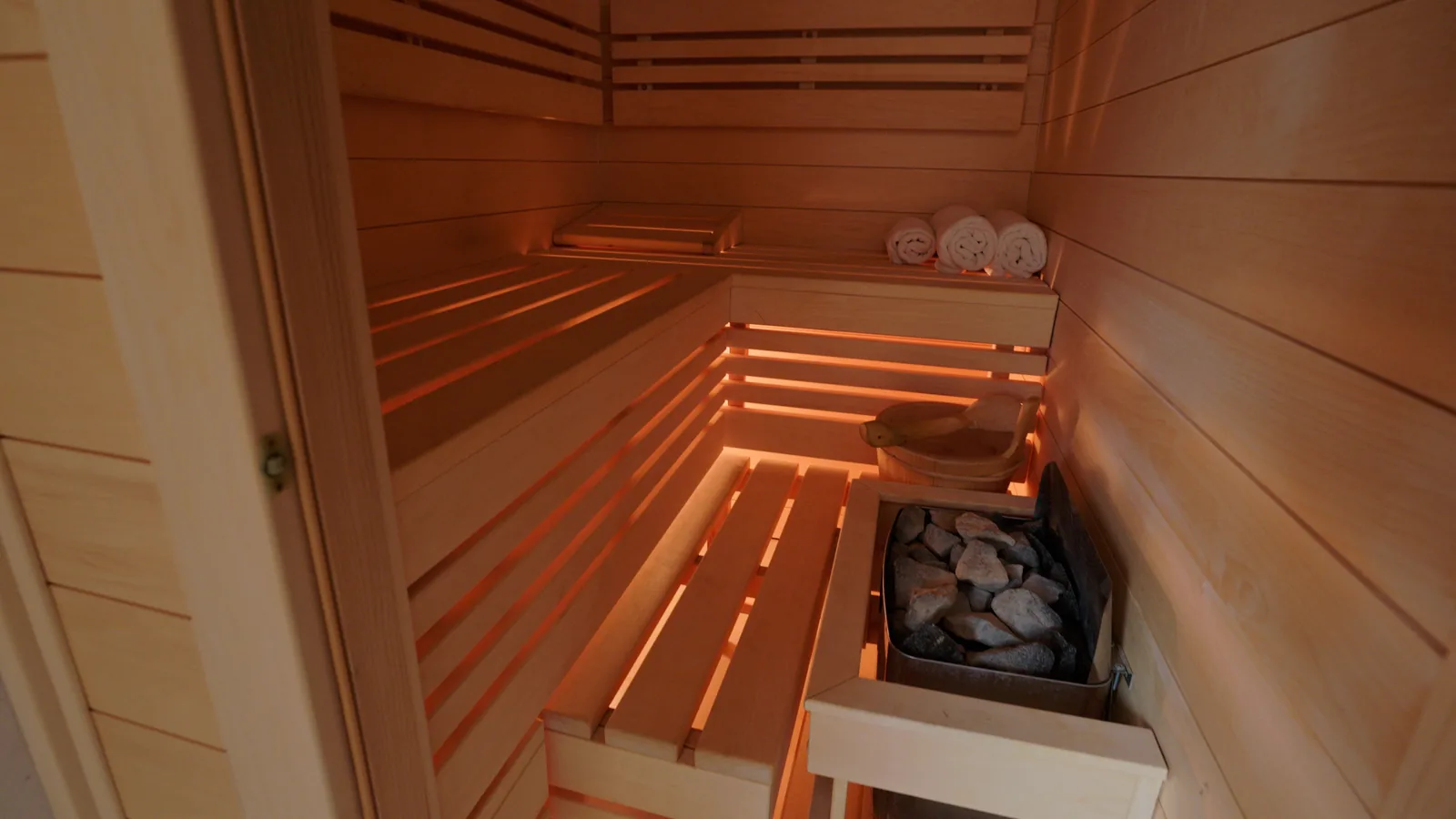 Sucha sauna fińska na poddaszu, wyłożona jasnym skandynawskim drewnem